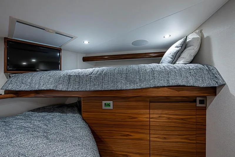 Slide: The Image of 2026 Viking 54 Convertible yacht interior with cozy bunk beds and modern TV setup. - 45