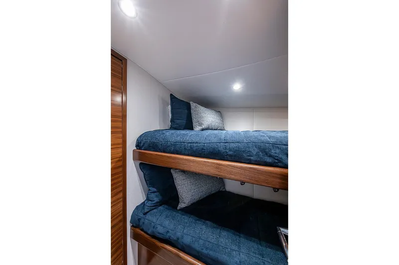 Slide: The Image of Bunk beds in 2026 Viking 54 Convertible yacht cabin with blue bedding and wooden accents. - 48
