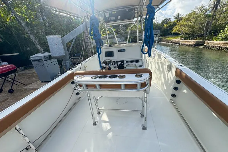 Slide: The Image of 2005 Sailfish 2660 CC boat interior with console and seating, docked by a scenic waterway. - 19