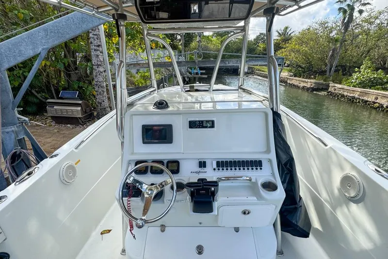 Slide: The Image of 2005 Sailfish 2660 CC boat cockpit with steering wheel and control panel, docked by a canal. - 23