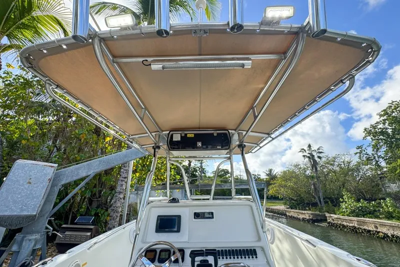 Slide: The Image of 2005 Sailfish 2660 CC boat with canopy, steering console, and lush tropical backdrop. - 35