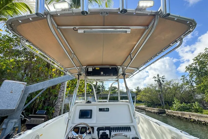 Slide: The Image of 2005 Sailfish 2660 CC boat with canopy, steering console, and lush tropical backdrop. - 36
