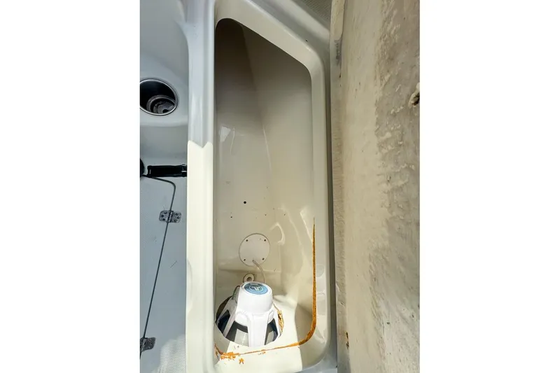 Slide: The Image of 2005 Sailfish 2660 CC boat storage compartment with visible wear and speaker. - 46