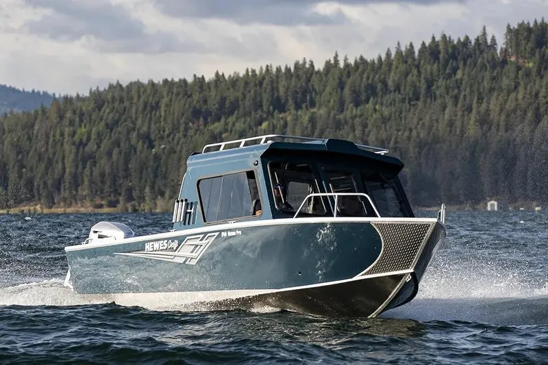 Slide: The Image of 2026 Hewescraft 240 Ocean Pro ET HT boat cruising on a scenic lake. - 11