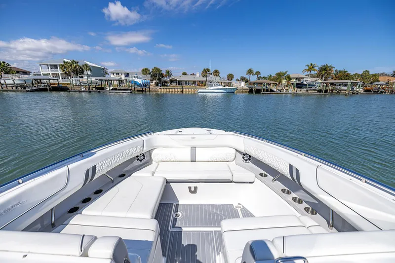 Slide: The Image of 2022 Regal LX36 boat with luxurious seating, docked near waterfront homes under a clear blue sky. - 12