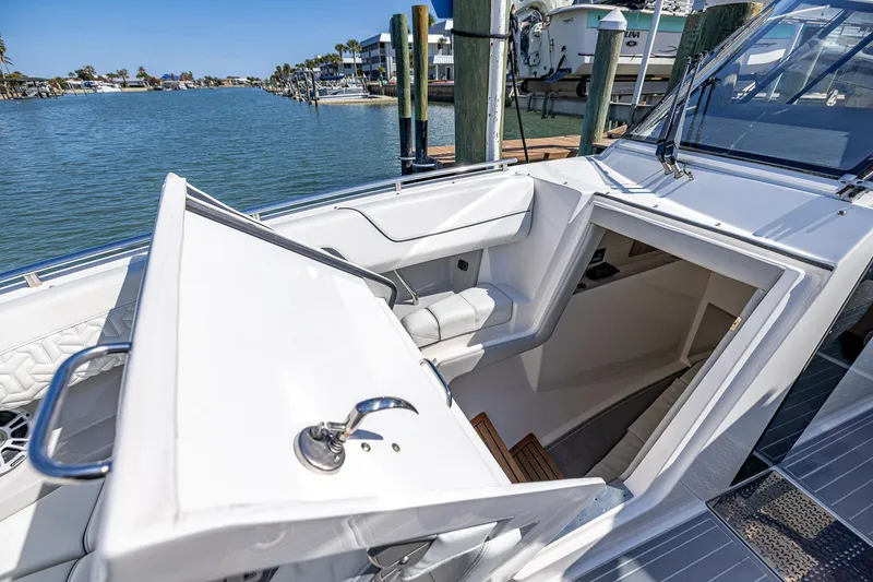 Slide: The Image of 2022 Regal LX36 boat interior with open cabin hatch, docked by the water. - 15