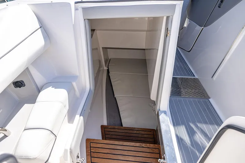 Slide: The Image of Interior cabin view of 2022 Regal LX36 boat, featuring sleek white seating and wooden steps. - 16