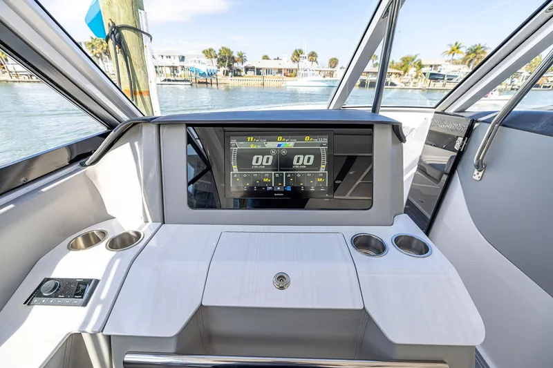 Slide: The Image of 2022 Regal LX36 boat dashboard with digital display and cup holders, docked by the water. - 27