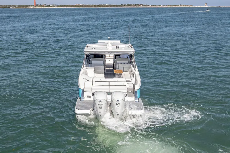 Slide: The Image of 2022 Regal LX36 boat cruising on open water, rear view. - 4