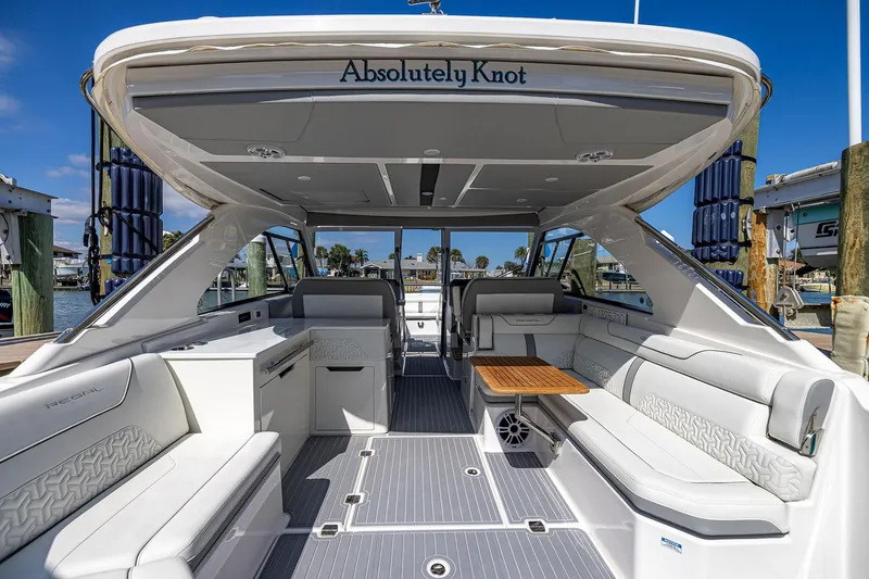 Slide: The Image of 2022 Regal LX36 luxury boat interior with white seating and wooden table, docked at marina. - 41