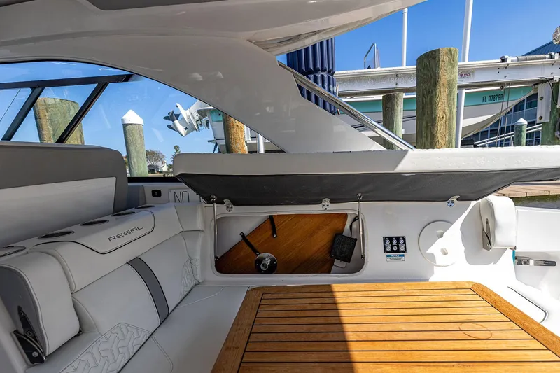 Slide: The Image of 2022 Regal LX36 boat interior with seating, wooden table, and storage compartment. - 43