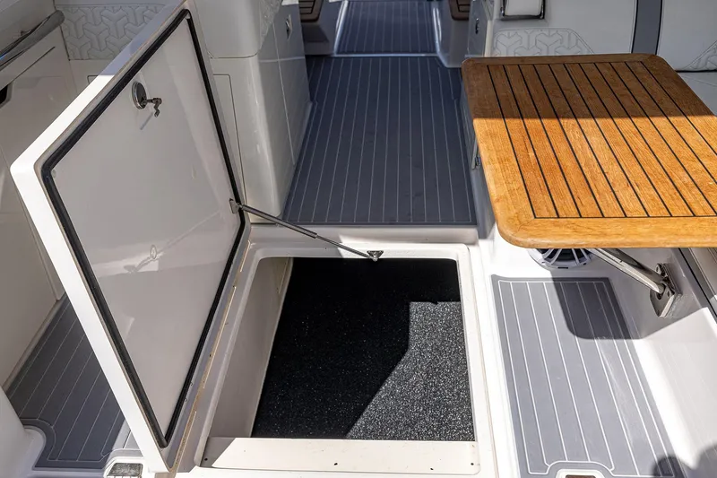 Slide: The Image of 2022 Regal LX36 boat interior with open storage hatch and wooden table. - 46