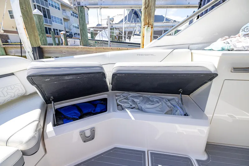 Slide: The Image of 2022 Regal LX36 boat with open storage compartments, docked at marina. - 56