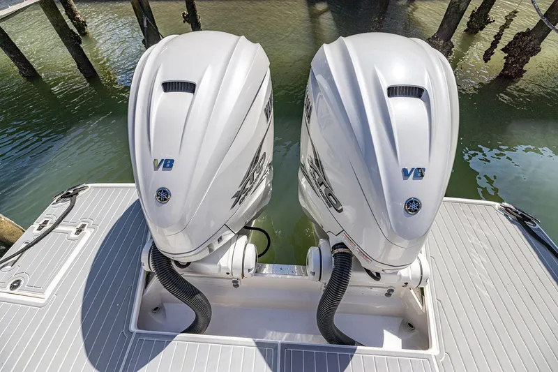 Slide: The Image of Twin outboard engines on a 2022 Regal LX36 boat, docked by the water. - 63