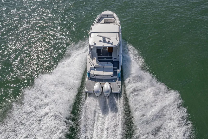 Slide: The Image of 2022 Regal LX36 boat cruising on open water, aerial rear view. - 70