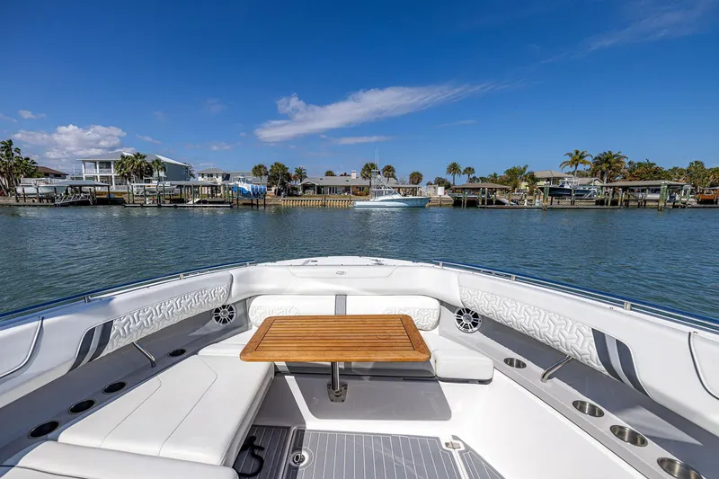 Slide: The Image of 2022 Regal LX36 boat interior with seating and table, docked by waterfront homes. - 9