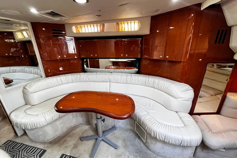 Slide: The Image of Luxurious interior of 1999 Sea Ray 380 Sundancer with curved seating and wooden table. - 18