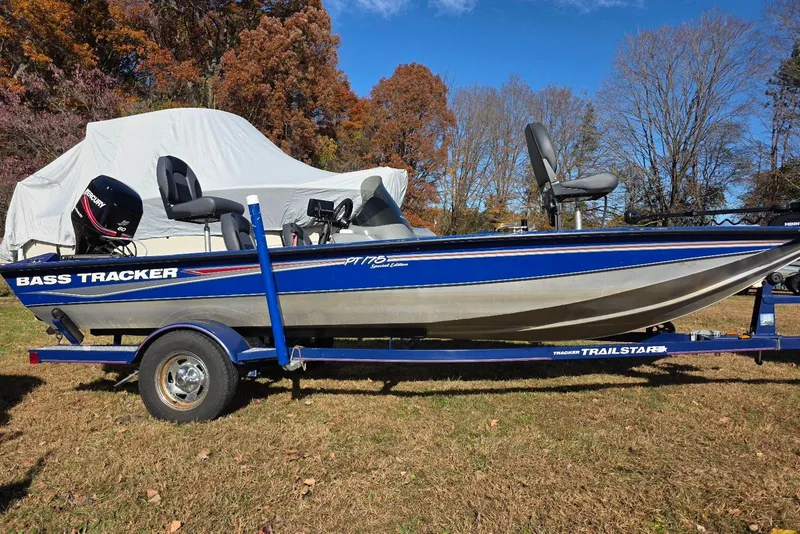 The Image of 2006 Tracker Pro Team 175 bass boat on trailer, parked on grass with autumn trees. - 0