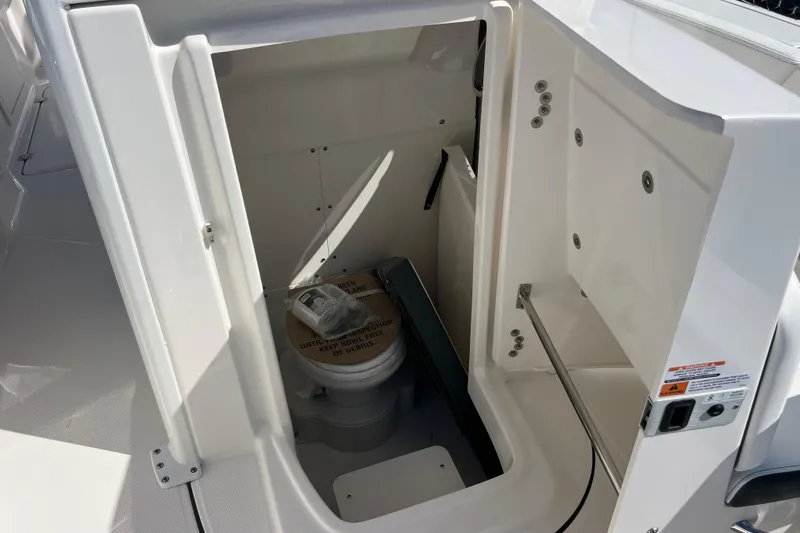Slide: The Image of 2026 Robalo R250 Center Console boat interior with compact marine toilet. - 10