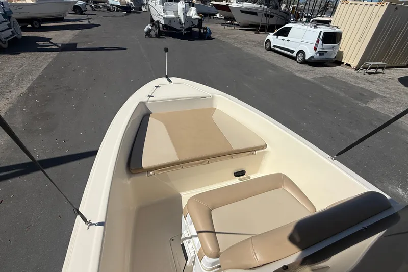 Slide: The Image of 2022 Scout 175 Sportfish boat interior with beige seating, parked in a marina. - 14