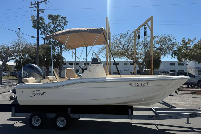 Slide: The Image of 2022 Scout 175 Sportfish boat on trailer, parked outdoors under clear sky. - 2