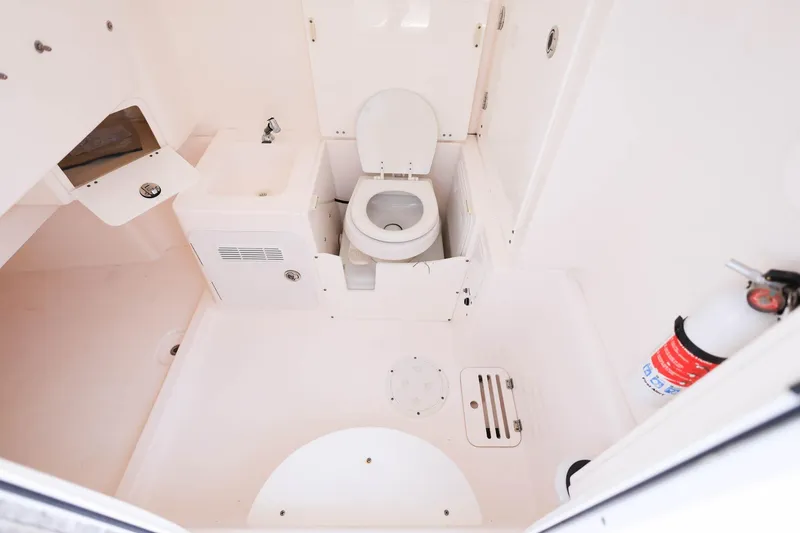 Slide: The Image of 2015 Everglades 355 Center Console boat bathroom with toilet, sink, and fire extinguisher. - 21