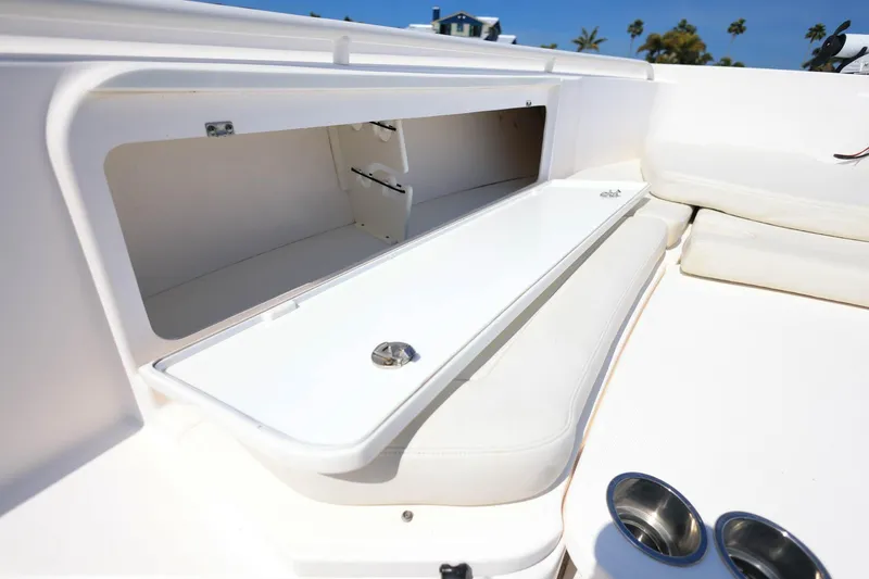 Slide: The Image of 2015 Everglades 355 Center Console boat storage compartment with open lid and cup holders. - 28