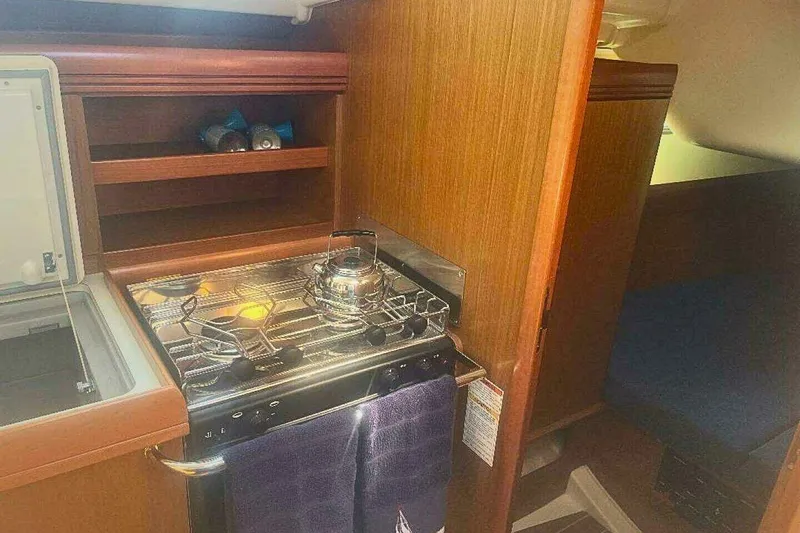 Slide: The Image of 2007 Jeanneau Sun Odyssey 39i yacht interior kitchen with stove and wooden cabinetry. - 24