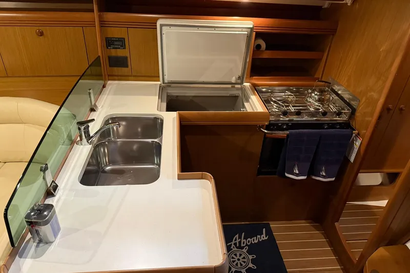 Slide: The Image of 2007 Jeanneau Sun Odyssey 39i yacht kitchen with sink, stove, and wooden cabinetry. - 38