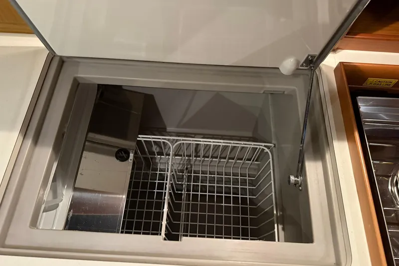 Slide: The Image of Open storage compartment on 2007 Jeanneau Sun Odyssey 39i yacht, featuring wire basket. - 41