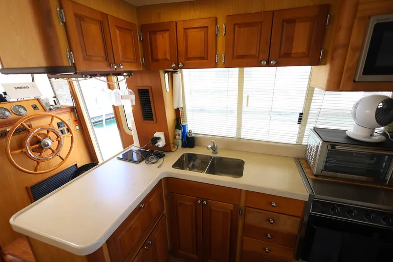 Slide: The Image of 2005 Mainship 40 Trawler kitchen with wooden cabinets, sink, and steering wheel. - 14