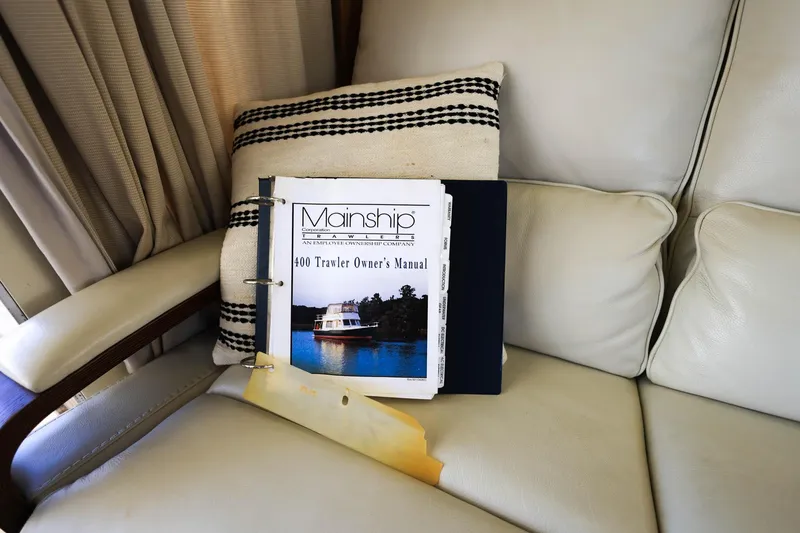 Slide: The Image of Owner's manual for 2005 Mainship 40 Trawler on a beige sofa. - 19