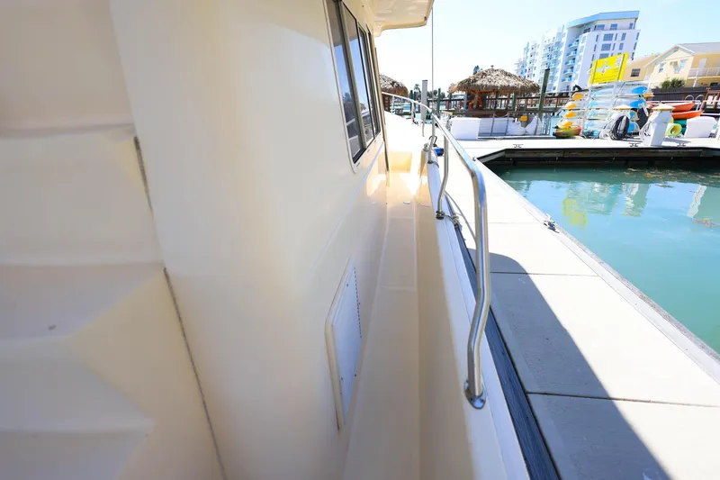 Slide: The Image of 2005 Mainship 40 Trawler docked, showcasing side deck and marina view. - 28