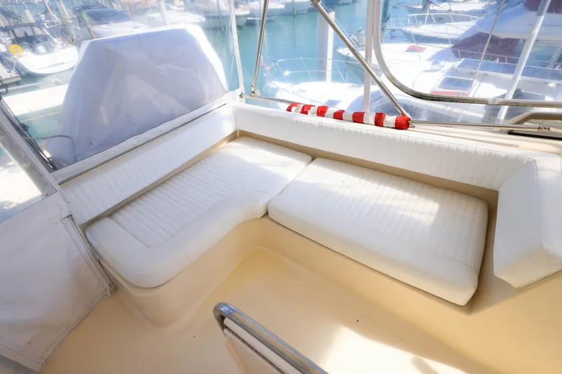 Slide: The Image of 2005 Mainship 40 Trawler interior with white cushioned seating and marina view. - 39