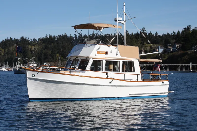 Slide: The Image of 1983 Grand Banks 32 Sedan boat on calm water, with scenic forested background. - 1