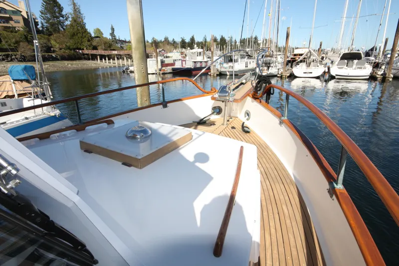 Slide: The Image of 1983 Grand Banks 32 Sedan boat docked in a marina, showcasing wooden deck and railings. - 18
