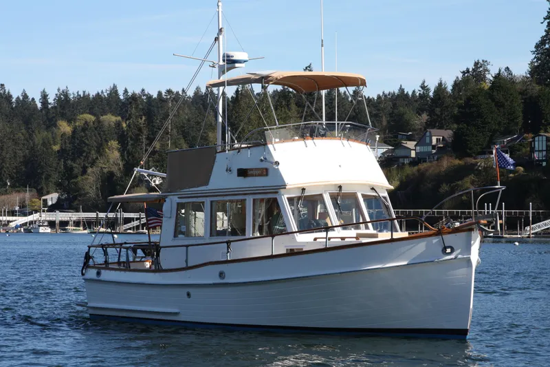 Slide: The Image of 1983 Grand Banks 32 Sedan cruising on a scenic lake with forested shoreline. - 4