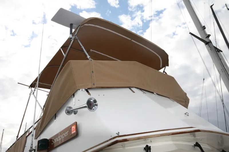 Slide: The Image of 1983 Grand Banks 32 Sedan boat with tan canopy under cloudy sky. - 42