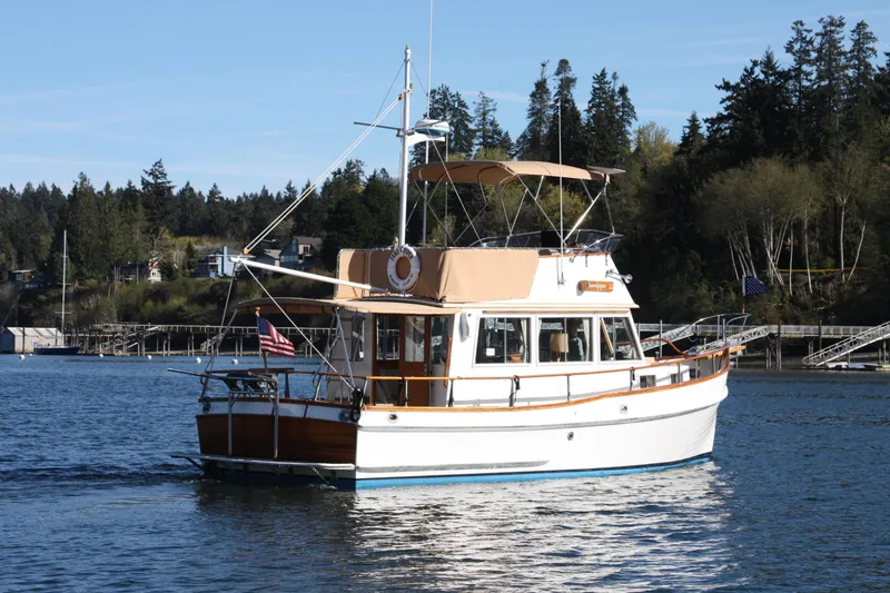 Slide: The Image of 1983 Grand Banks 32 Sedan cruising on a serene lake with forested shoreline. - 43