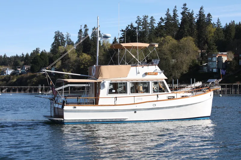 Slide: The Image of 1983 Grand Banks 32 Sedan cruising on a serene lake with forested shoreline. - 5