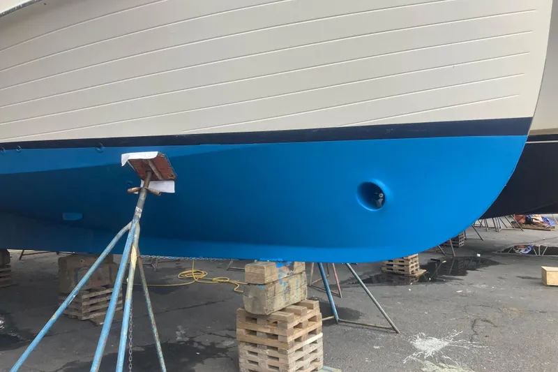 Slide: The Image of 1983 Grand Banks 32 Sedan boat hull on stands, freshly painted blue and white. - 58
