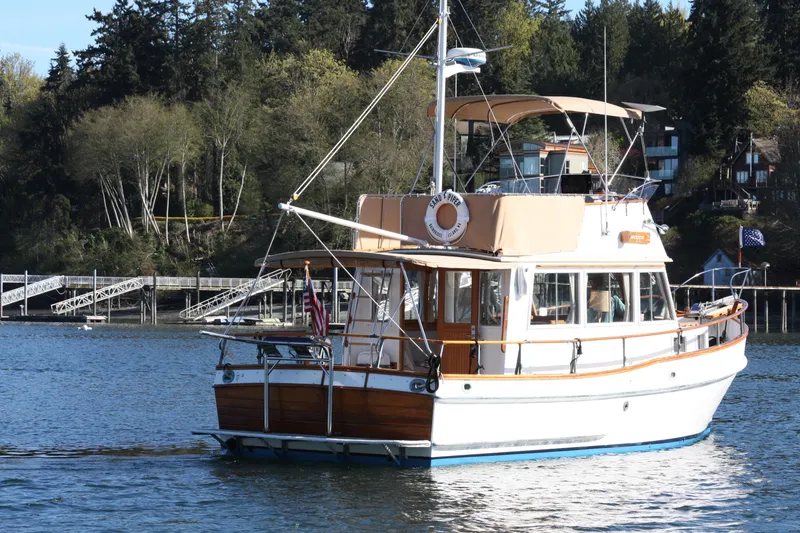 Slide: The Image of 1983 Grand Banks 32 Sedan cruising on a serene lake with forested shoreline. - 6