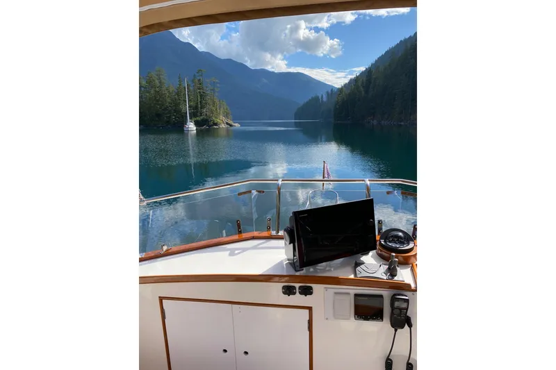 Slide: The Image of 1983 Grand Banks 32 Sedan navigating serene lake with lush forested mountains. - 70