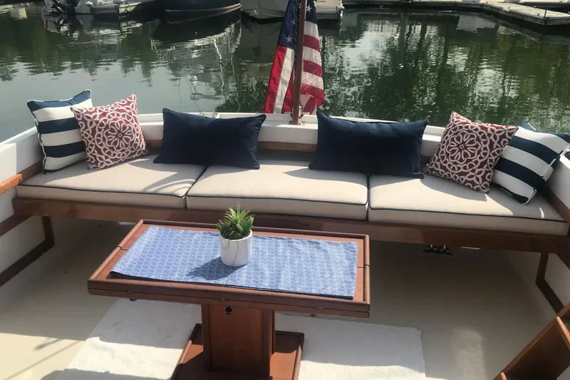 Slide: The Image of Cozy seating area on 1987 Wilbur 38 boat with decorative cushions and table. - 13