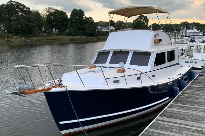Slide: The Image of 1987 Wilbur 38 boat docked on calm water with trees in the background. - 2