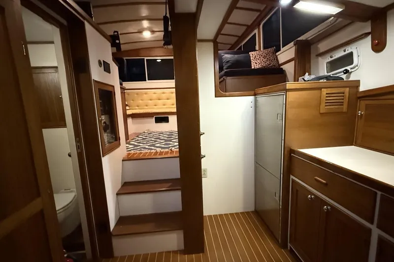 Slide: The Image of Interior of 1987 Wilbur 38 boat with wooden cabinetry and cozy seating area. - 21