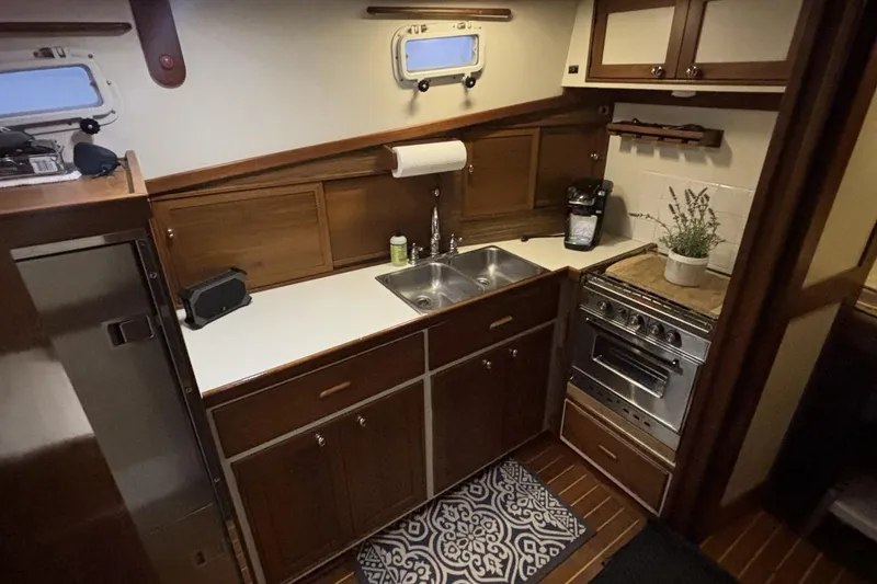 Slide: The Image of Compact kitchen in a 1987 Wilbur 38 boat, featuring wooden cabinets and stainless steel appliances. - 22