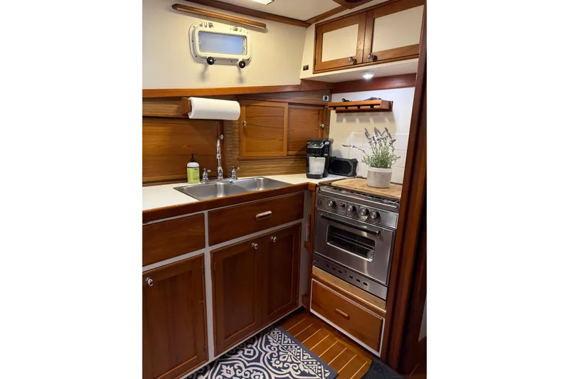 Slide: The Image of Compact 1987 Wilbur 38 boat kitchen with wooden cabinets, stainless steel sink, and oven. - 24
