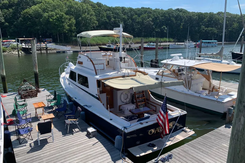 Slide: The Image of 1987 Wilbur 38 yacht docked at marina with outdoor seating and American flag. - 47