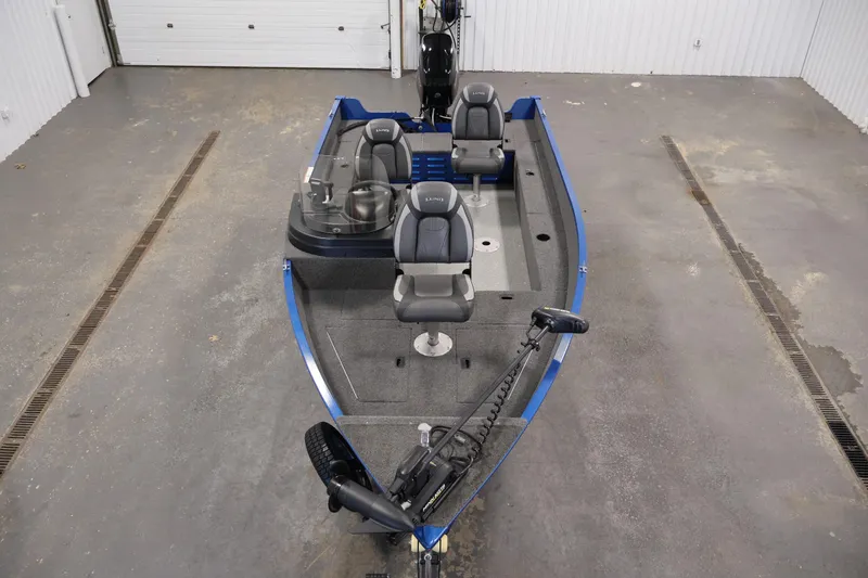 Slide: The Image of 2021 Lund 1650 Angler Sport fishing boat in a garage, featuring seating and trolling motor. - 9